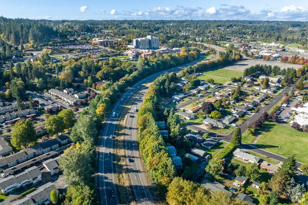 Aerial view of Puyallup, WA, with a highway, neighborhoods, and autumn trees under a clear sky.