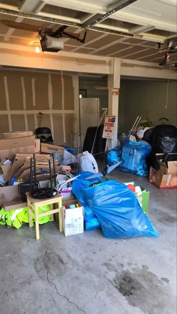 A cluttered garage filled with boxes, bags, and household items awaiting junk removal.